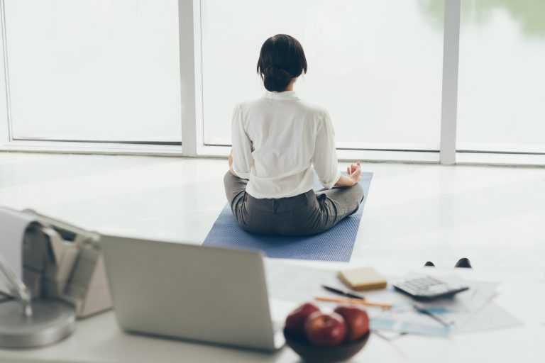 Office worker meditating on the floor, rear view health wellness wellbeing work life balance