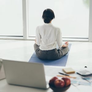 Office worker meditating on the floor, rear view health wellness wellbeing work life balance