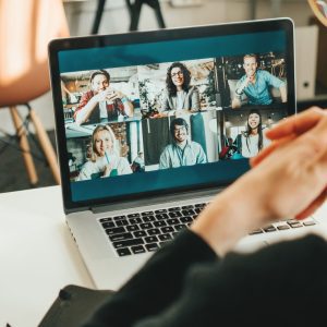 Woman has video conference with her remote team using laptop and camera