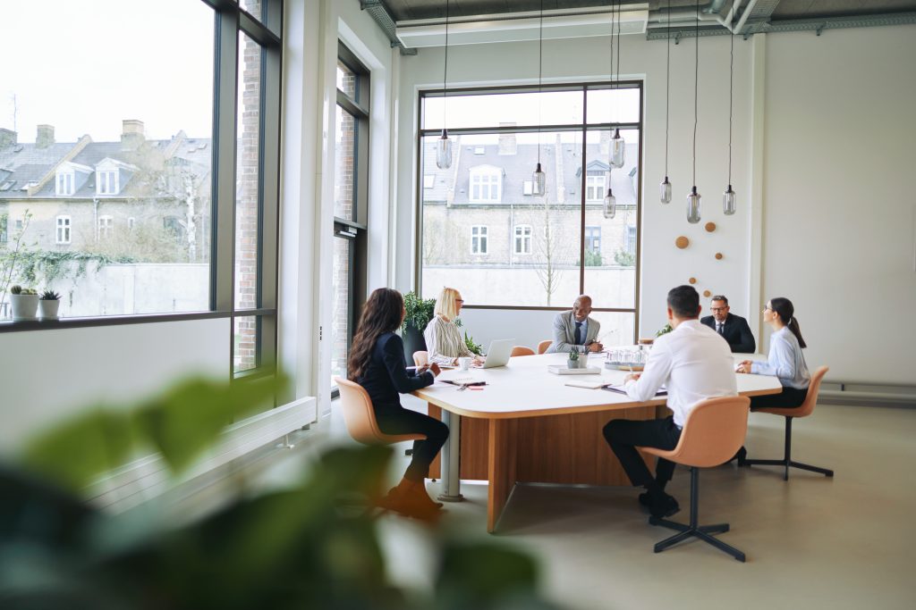 workplace employees employer engagement meeting team strategy planning leaders communication Smiling group of diverse businesspeople sitting around a boardroom table in an office during a meeting