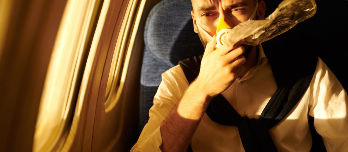 Portrait of handsome young man wearing oxygen mask in plane, copy pace