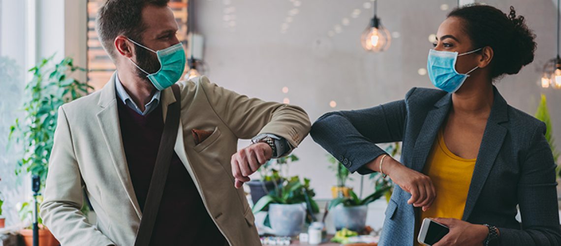 Colleagues in the office practicing alternative greeting to avoid handshakes during COVID-19 pandemic