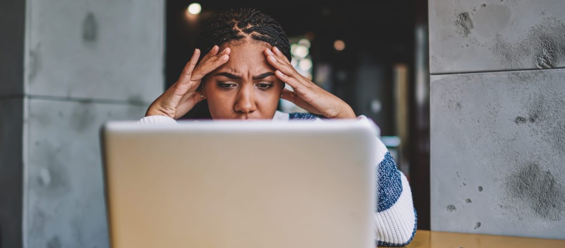 Confused female freelancer reading new task from work during distance job with laptop device in coworking space, unhappy woman have problem with payment via modern netbook feeling headache indoors