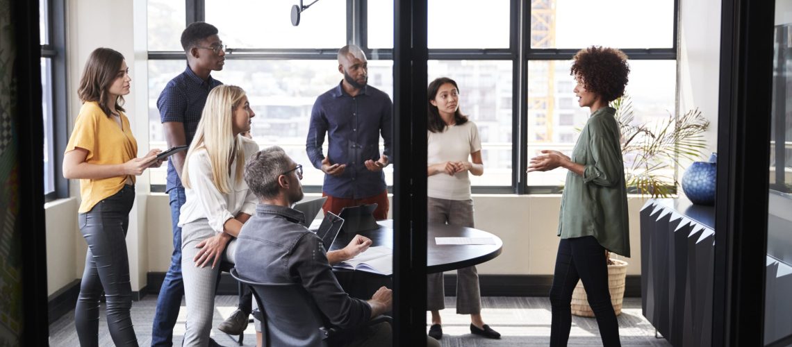 Creative business team listening to their female colleague presenting at a brainstorm meeting