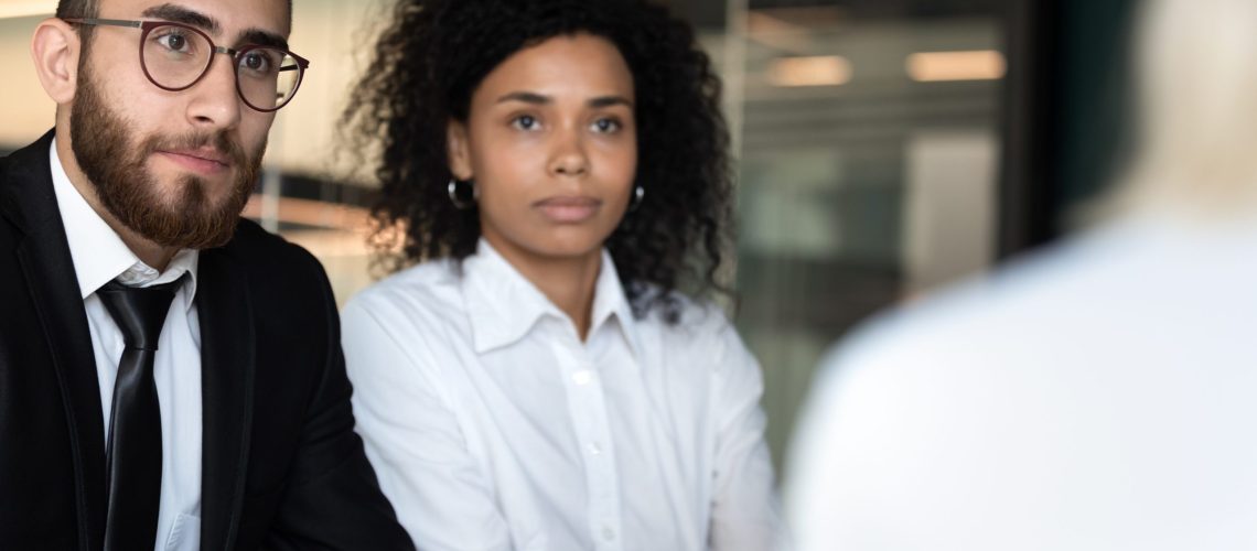 Diverse hr managers listening to job applicant close up, African American businesswoman and businessman wearing glasses holding interview, looking at job seeker, business partners at meeting