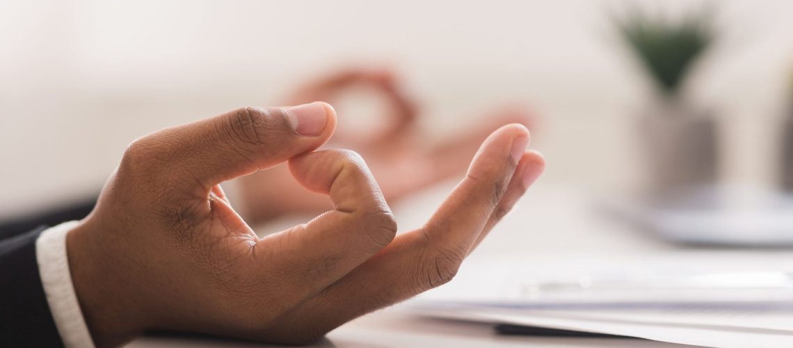 Close up of black businessman hands meditating at workplace, burnout concept