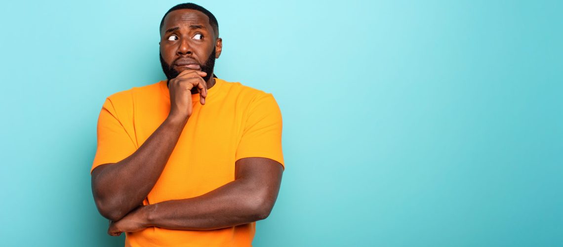 Confuse and pensive expression of a black boy. cyan colored background