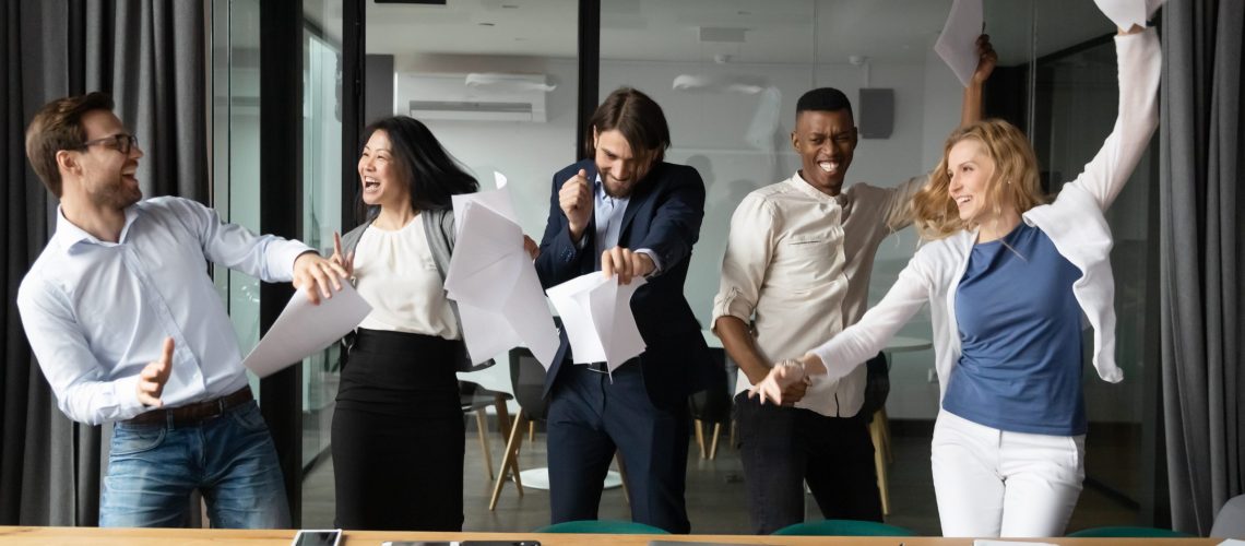 Overjoyed multiethnic colleagues have fun celebrating in office culture employees happy excited positive work environment team talent