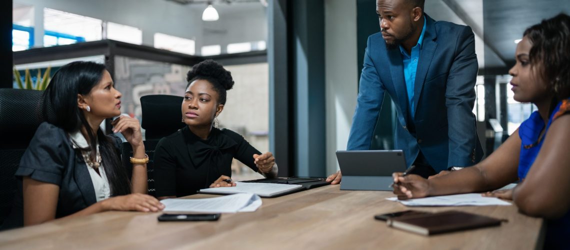 Young African businessman talking with his team during a meeting around a boardroom table in an office