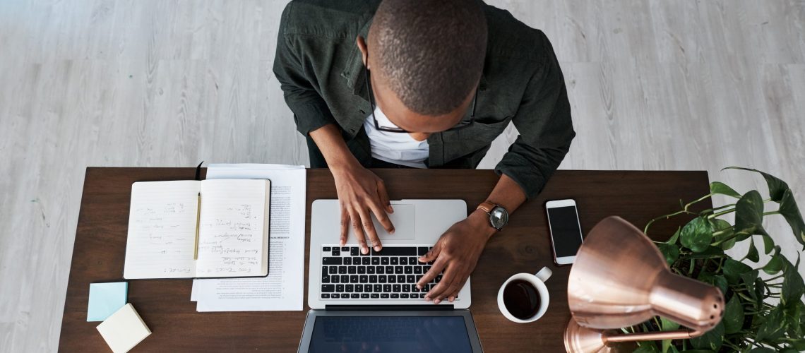 Shot of a young businessman typing on his laptop while working from home.