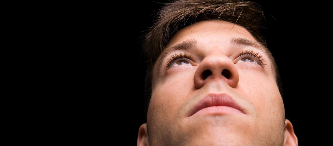 Young man looking up on black background