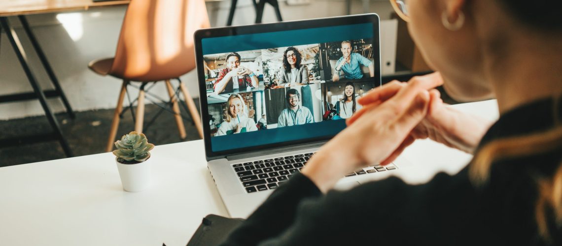 Woman has video conference with her remote team using laptop and camera