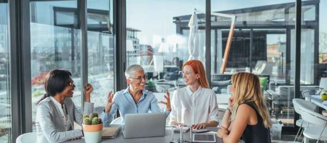 Team of female workers discussing laughing happy