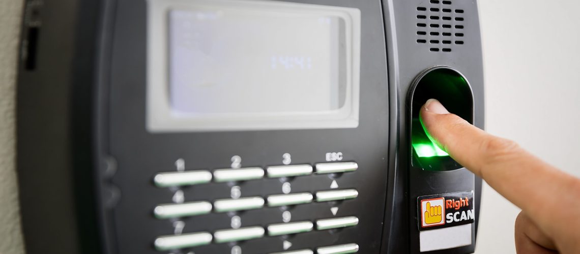 Woman hand scanning finger on machine to record working time.