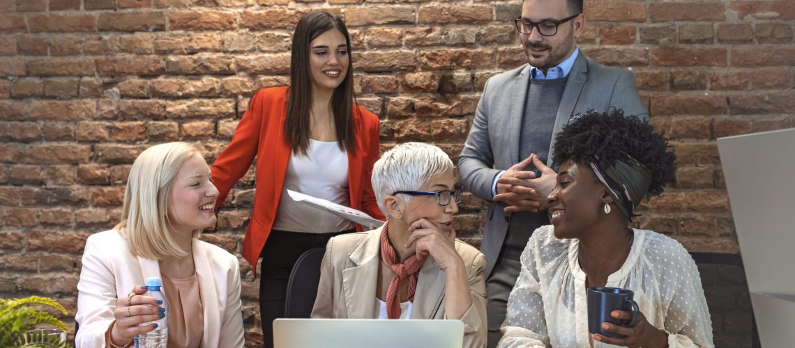 Shot of a group of businesspeople sitting together in a meeting. Group of people on a business meeting.  Aged businesswoman, teacher or business coach speaking to young people