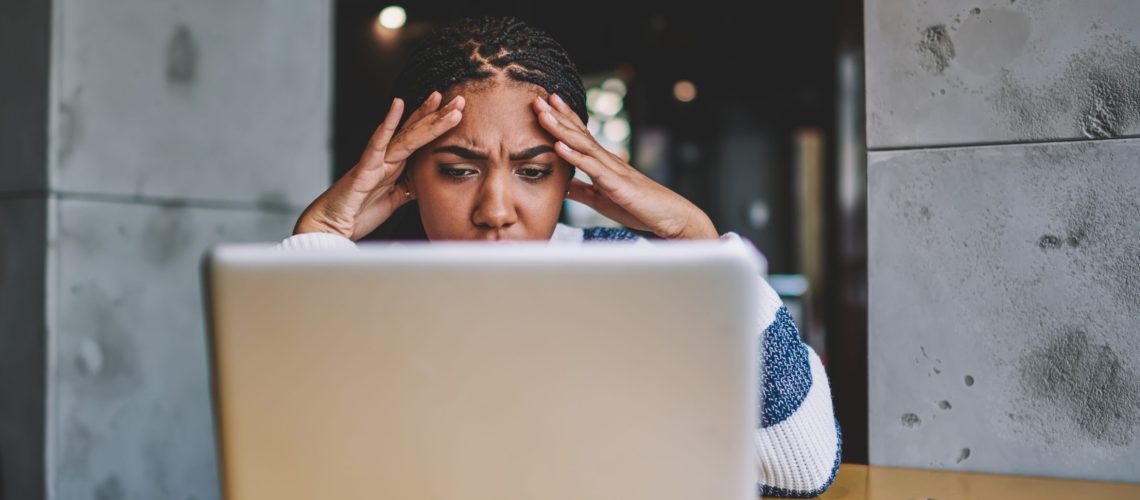 Confused female freelancer reading new task from work during distance job with laptop device in coworking space, unhappy woman have problem with payment via modern netbook feeling headache indoors