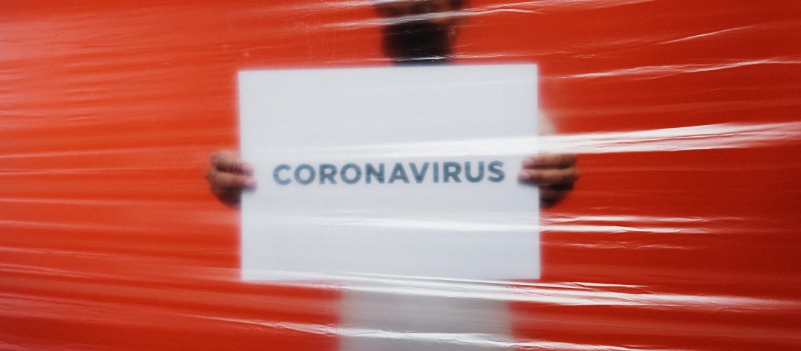 man-behind-a-plastic-holding-a-poster-of-coronavirus-3952185