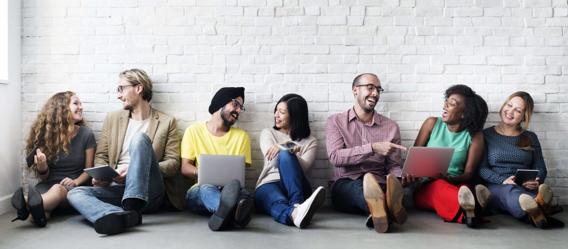 team sitting against wall happy laughing diversity