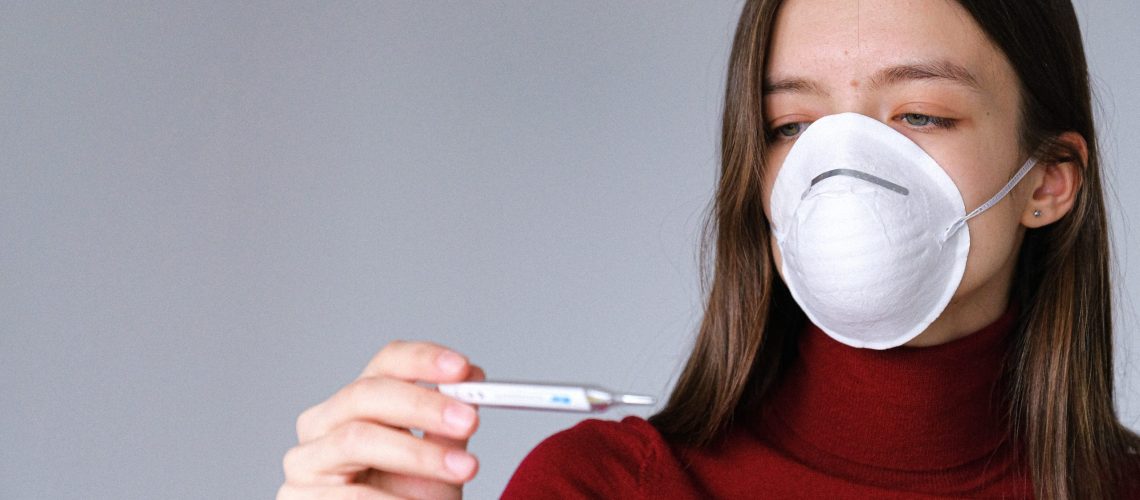 woman-in-face-mask-checking-thermometer-3987152