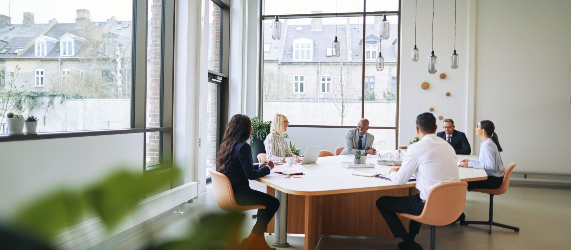 workplace employees employer engagement meeting team strategy planning leaders communication Smiling group of diverse businesspeople sitting around a boardroom table in an office during a meeting