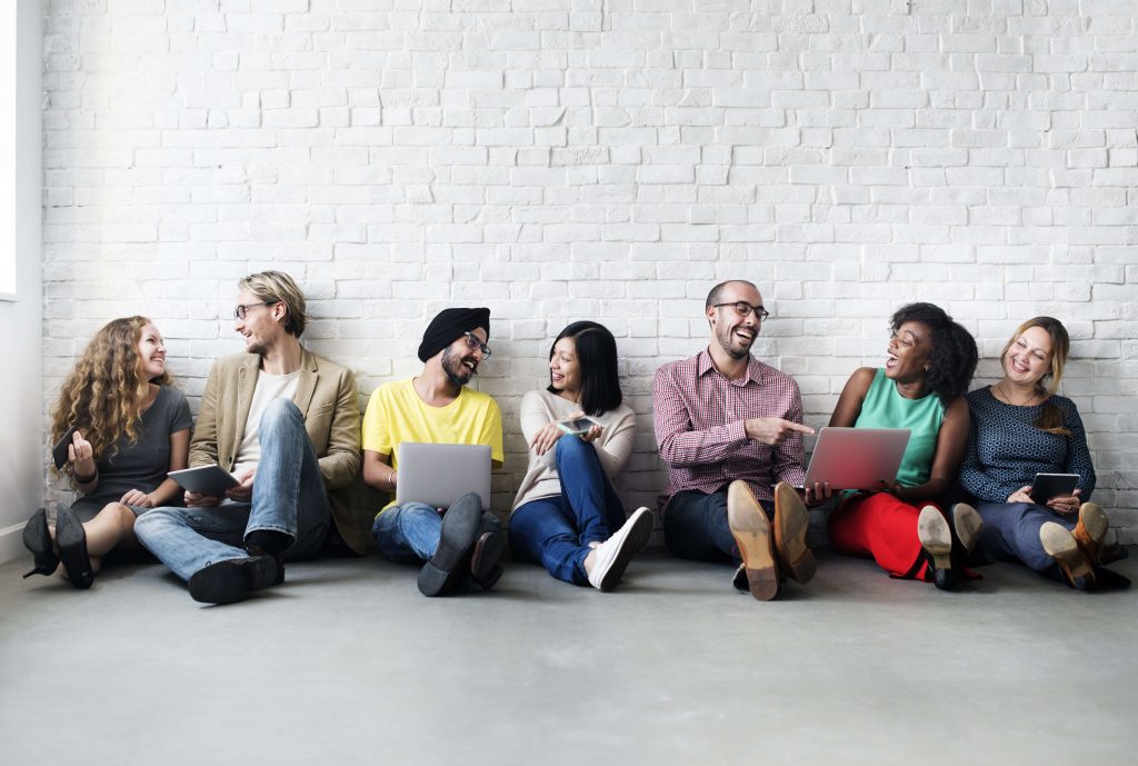 team sitting against wall happy laughing diversity