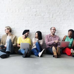 team sitting against wall happy laughing diversity